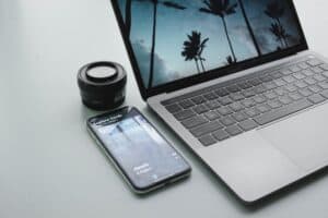 turned-on MacBook Pro beside black smartphone on gray surface